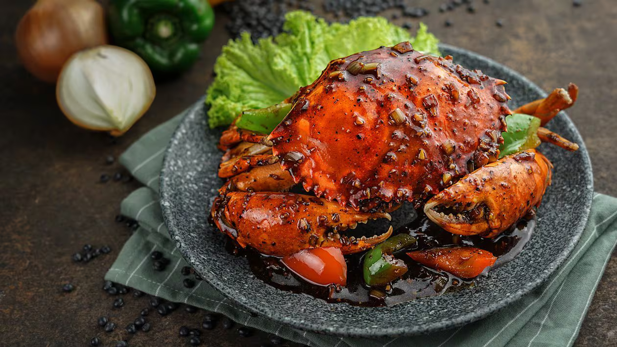 a crab cooked with black pepper sauce served in a palate