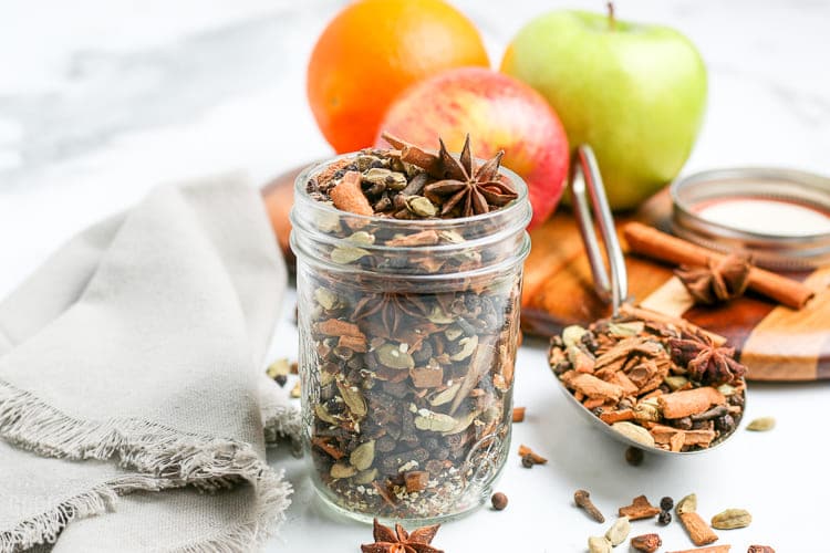 a jar filled with all spice mix and some oranges in the side