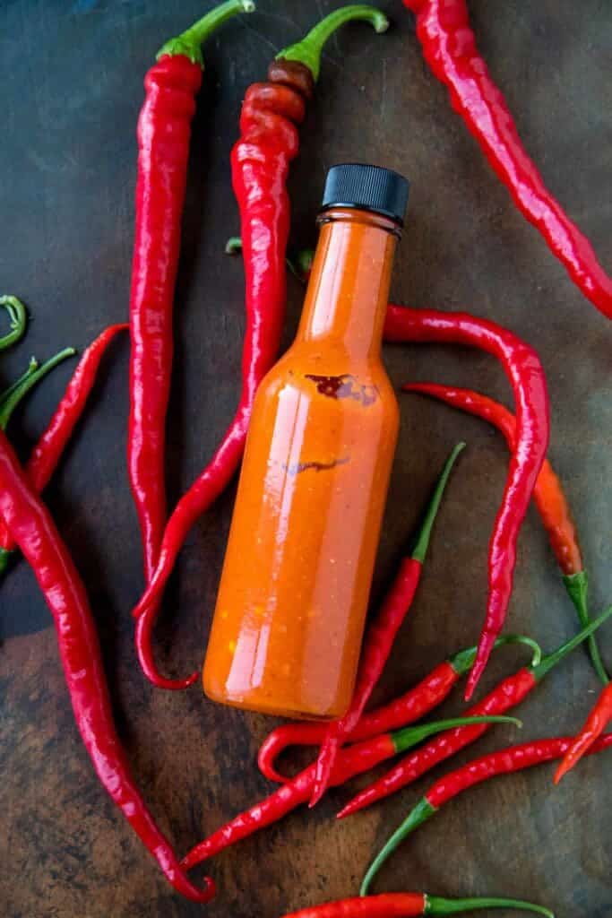 cayenne pepper saucr in a bottle some peppers on the side