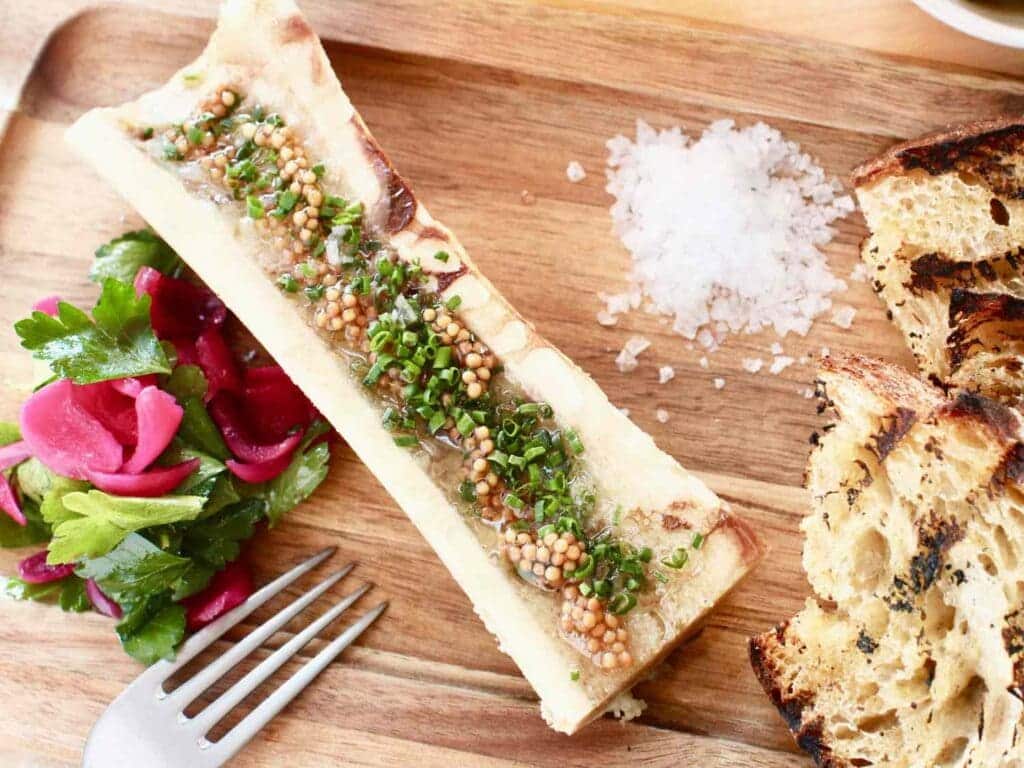 mustard seed pickle on bone marrrow along with bread and some salad