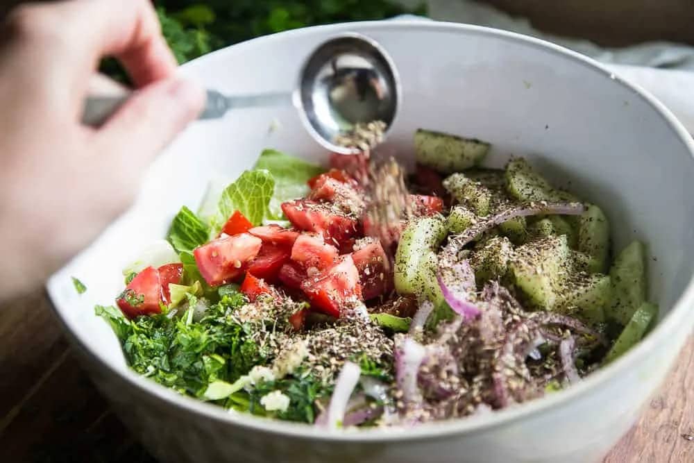 salad with zaatar seasoning tomatoes cucumber onions in a white bowl