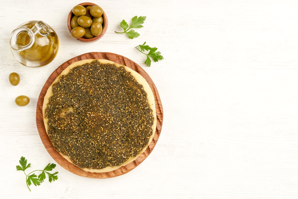 Zaatar manakeesh on wooden board with olives and olive oil