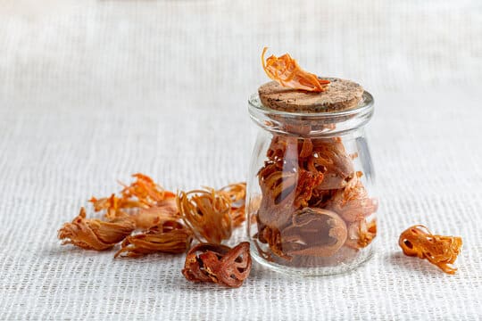 a jar full of mace spice along with some spice lying nearby on the surface