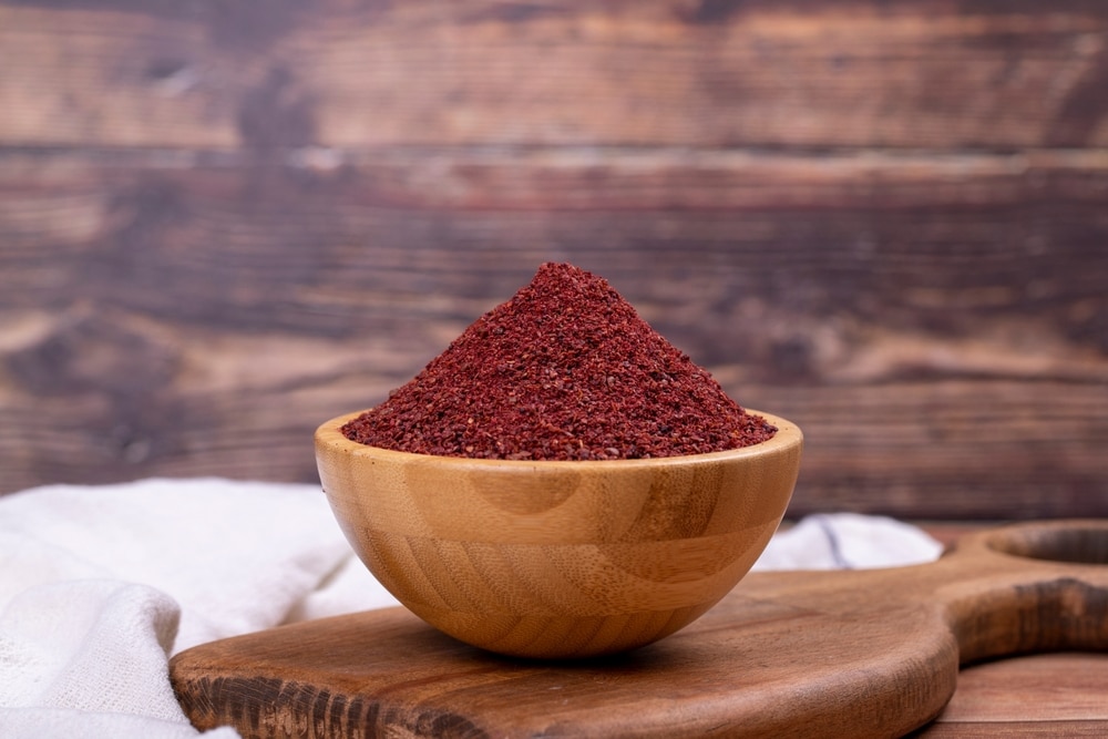 Dried ground red Sumac powder spices in wooden bowl