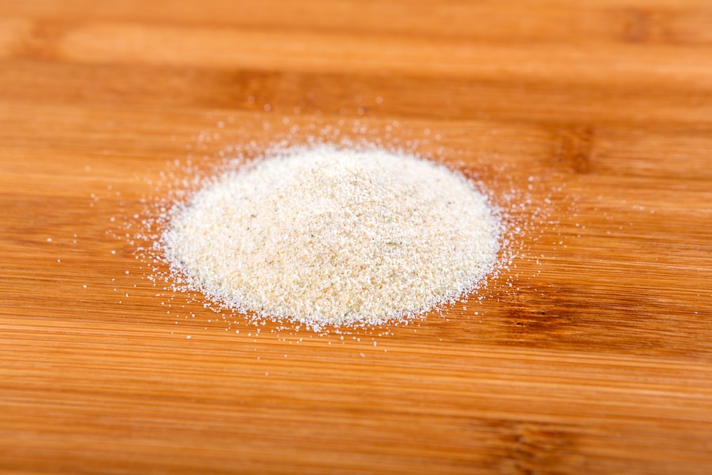 Pile Of Granulated Onion Isolated On Wood Background