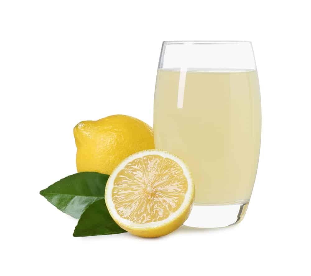 Refreshing lemon juice in glass, leaves isolated on white