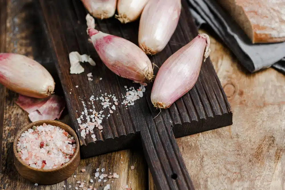 Shallots on a wooden background, salt and a textile napkin next to it