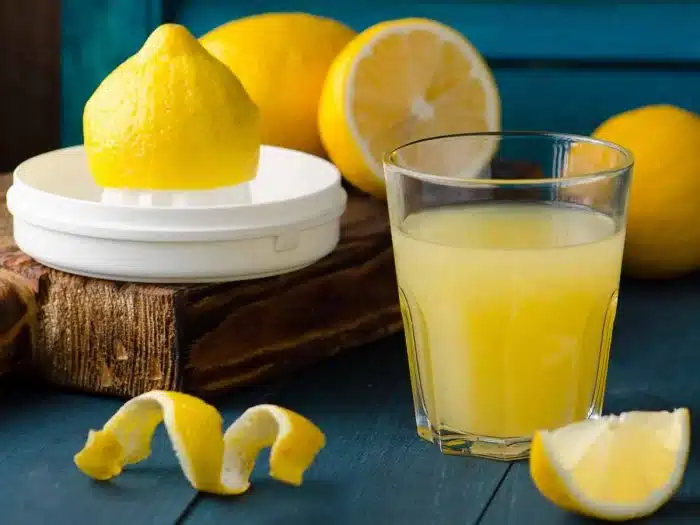 lemon juice in a glass half cut lemons placed alongside