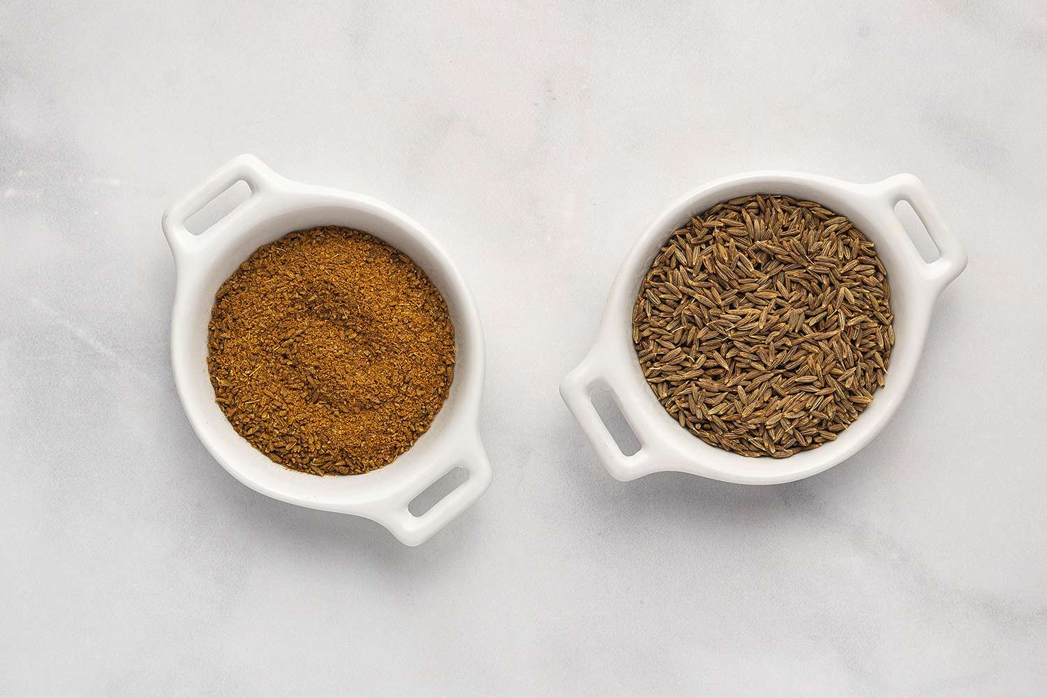 ground and whole cumin seeds in small white bowls