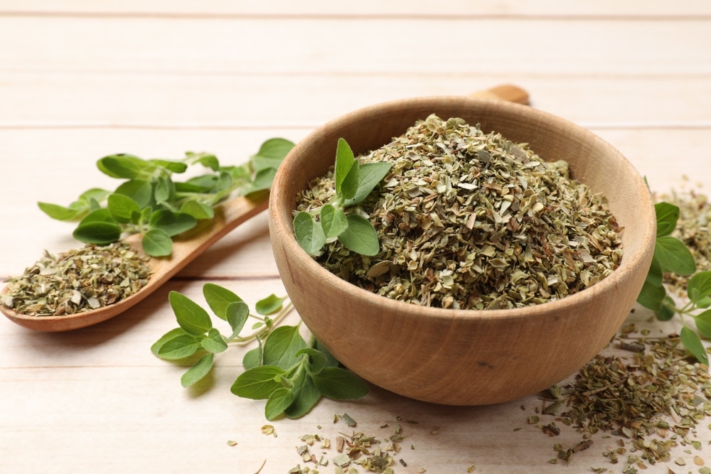 Dried Oregano In Bowl Spoon And Green Leaves On Wooden