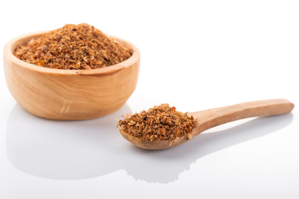 Ras el hanout in wooden bowl, on white background.